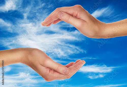 female hands over blue sky with clouds