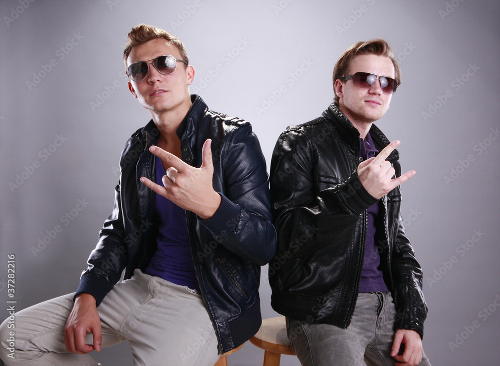 Two young men in leather making hand signs Two young men in leather making hand signs
