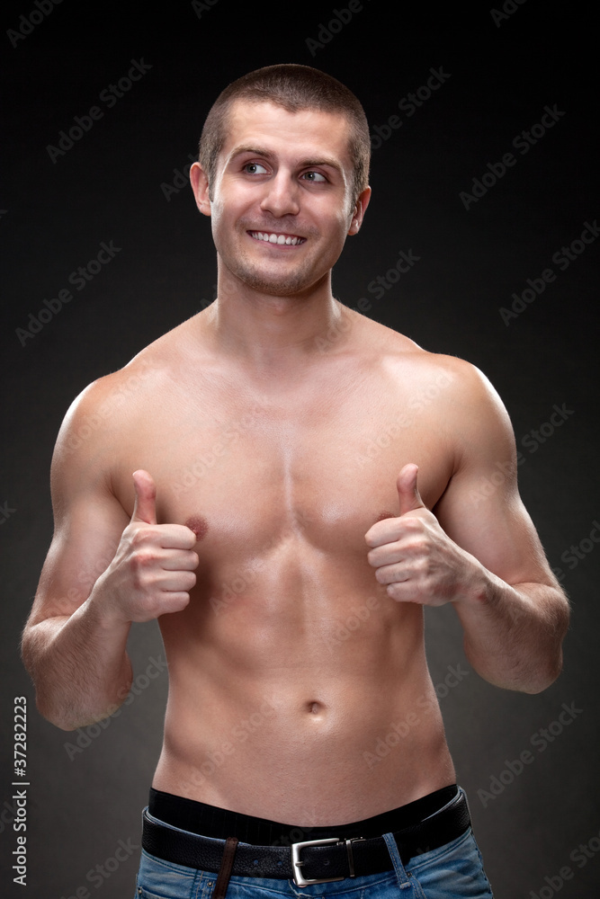 Fototapeta premium Handsome male with muscular body showing thumb up signs