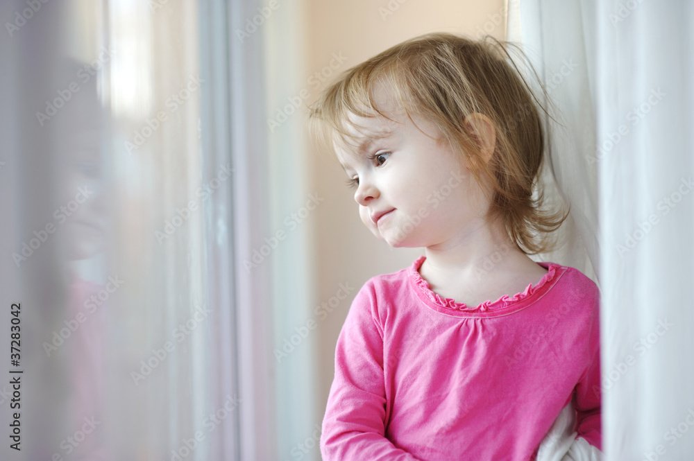 Adorable smiling little girl by the window Adorable smiling little girl by the window