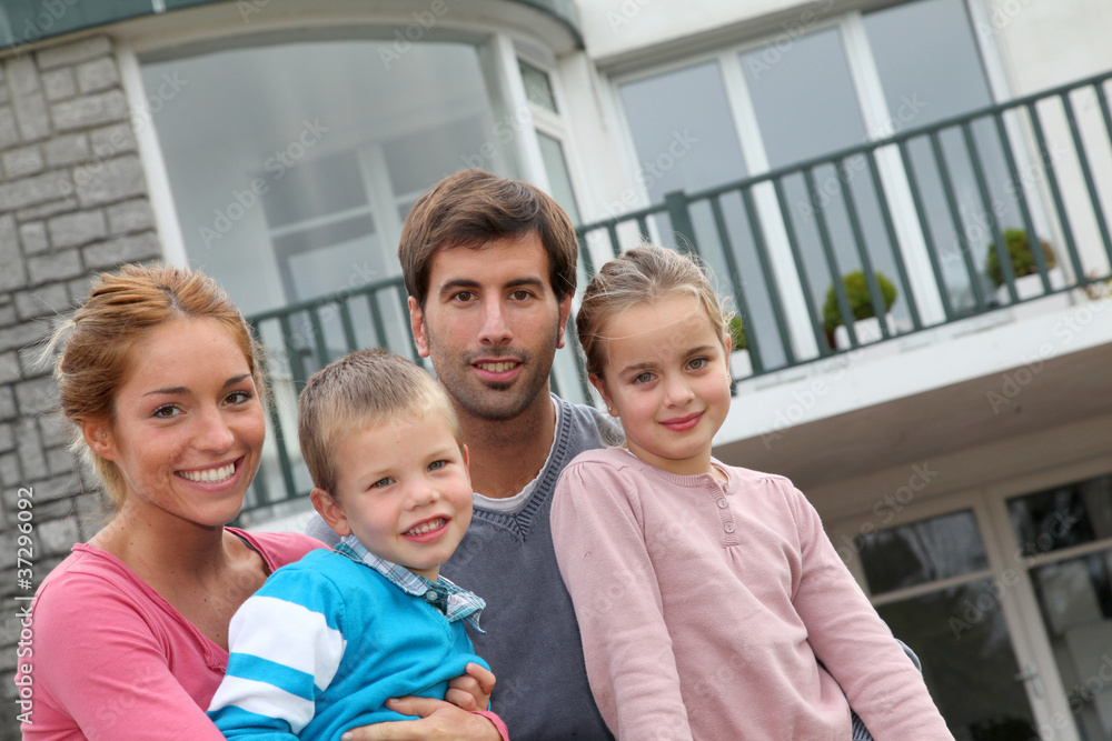 Happy family of 4 people sitting in front of new home Happy family of 4 people sitting in front of new home