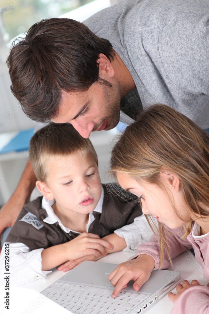 Man teaching kids how to use laptop computer Man teaching kids how to use laptop computer