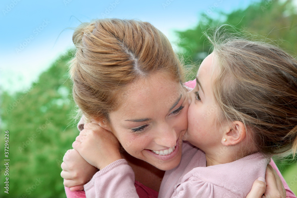 Portrait of little girl giving kiss to her mom Portrait of little girl giving kiss to her mom