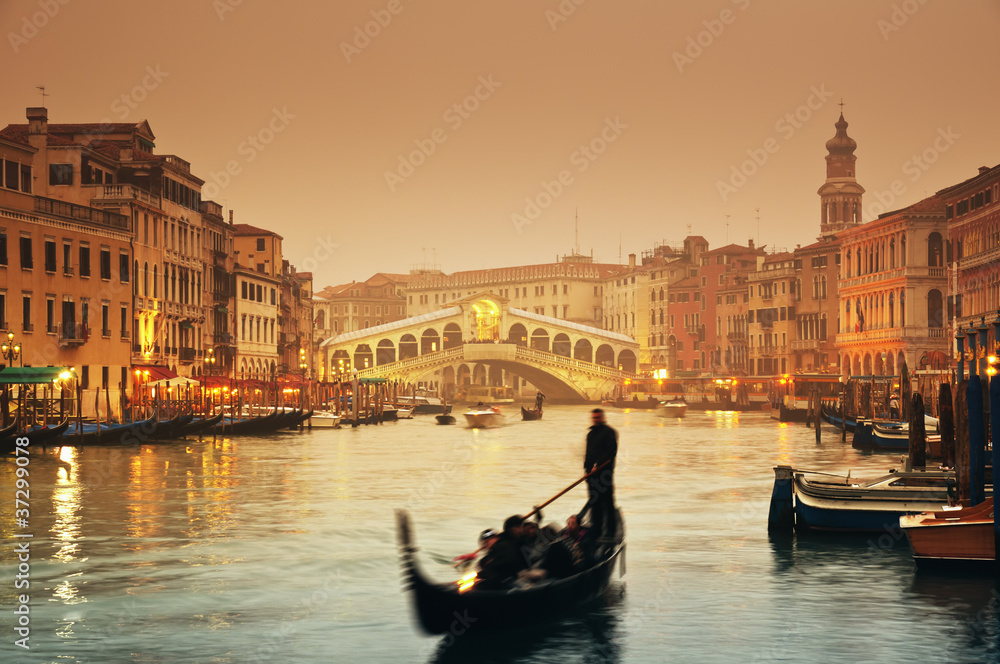 Naklejka premium Rialto most i gondole przy mgłowym jesień wieczór w Wenecja.
