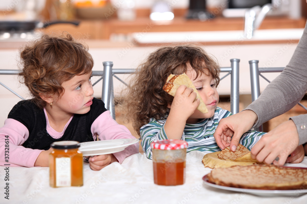 Two children at kitchen table having breakfast Two children at kitchen table having breakfast