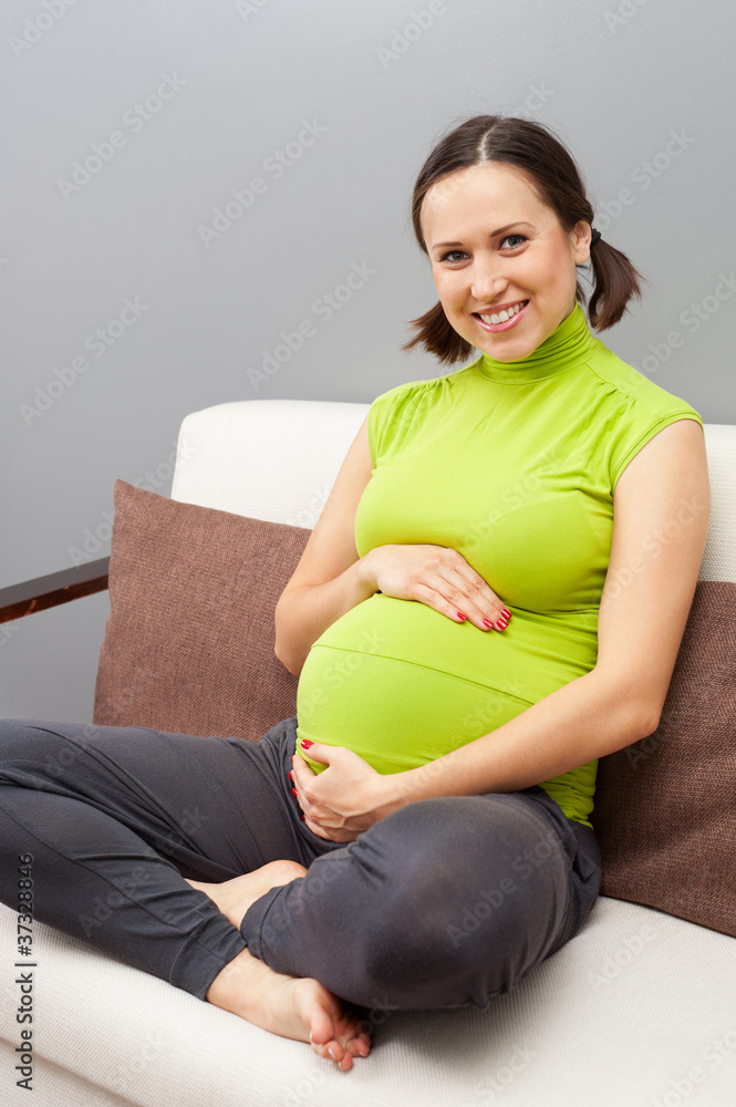 Obraz premium smiley pregnant woman sitting on sofa