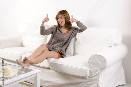 Young woman thumbs up on the sofa
