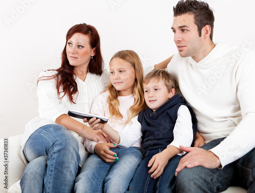 Cheeful young family watching TV at home