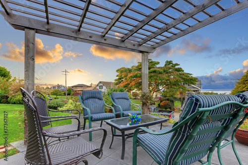 Fotografi Sunset over garden gazebo with chairs.