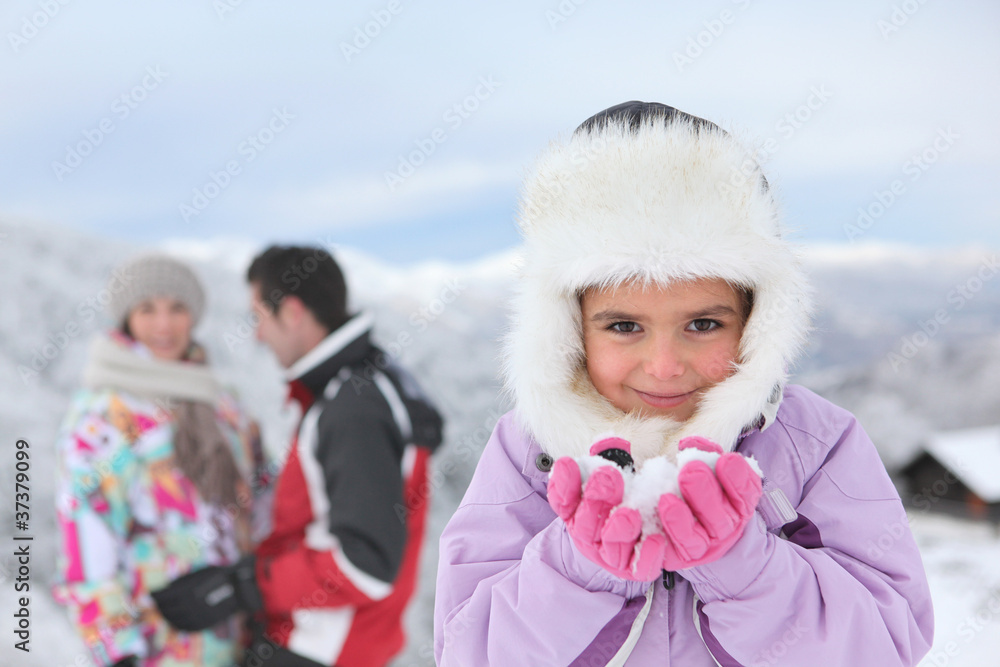 Little girl playing in the snow with her parents
