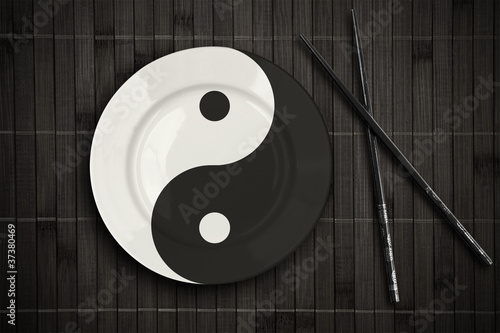 yin yan plate over bamboo placemat setting with sticks