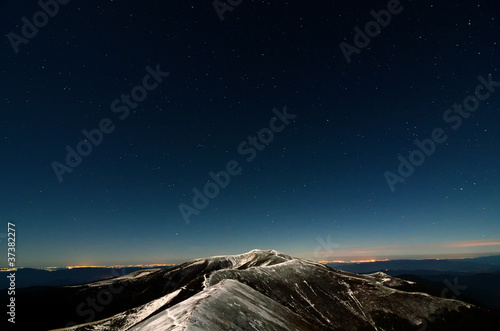 Glittering stars above snowy autumn mountain ridge
