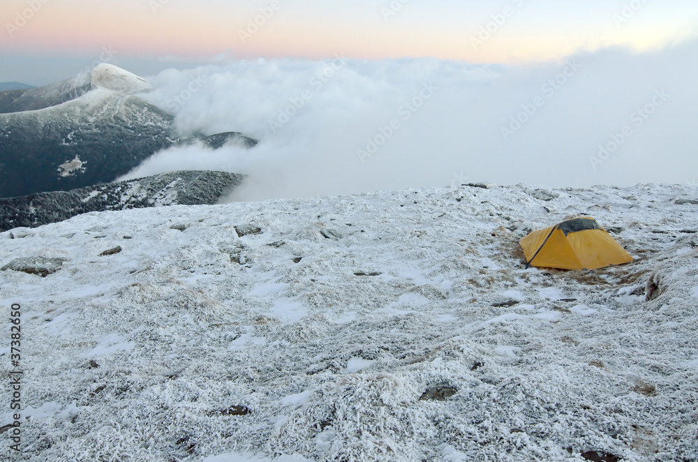 yellow touristic tent on a snowy peak