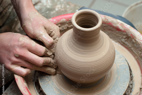 hands of a potter, creating an earthen jar on the circle