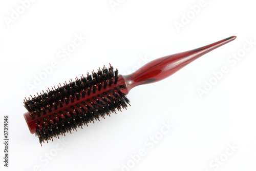 Red wooden handle hairbrush on fabric.