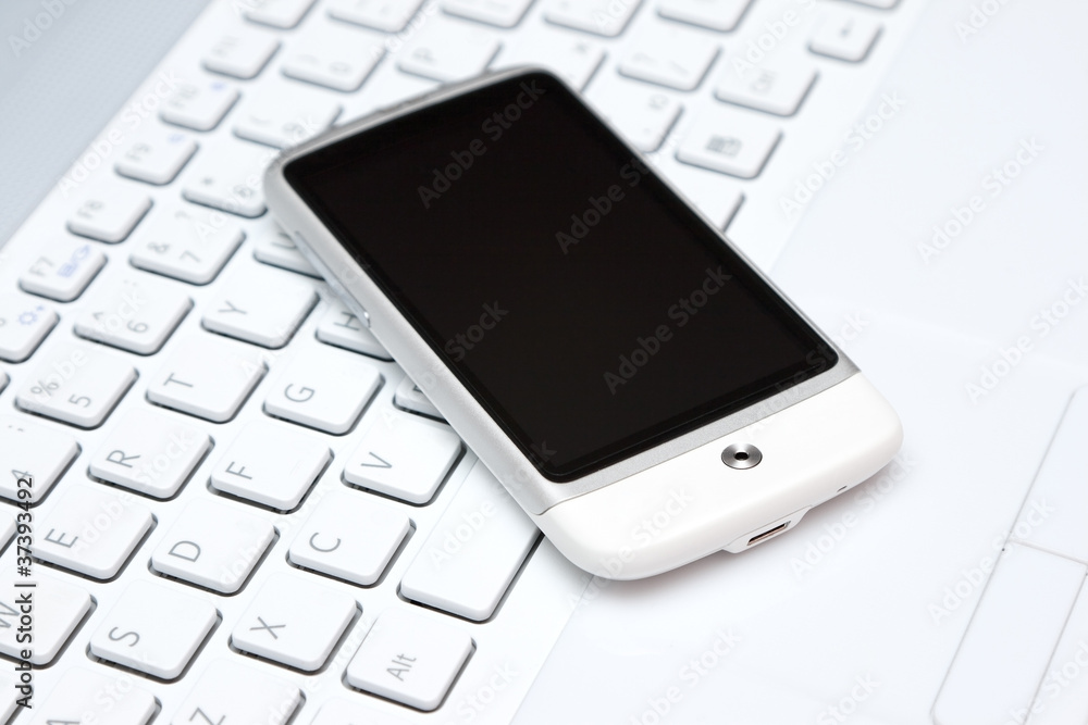 smart phone over white keyboard smart phone over white keyboard