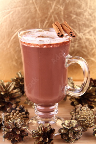 Cup of hot chocolate with cinnamon sticks and gold cones