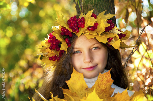 Cute smiling girl in a wreath of red viburnum on the head