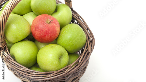 basket with green apples and one red one