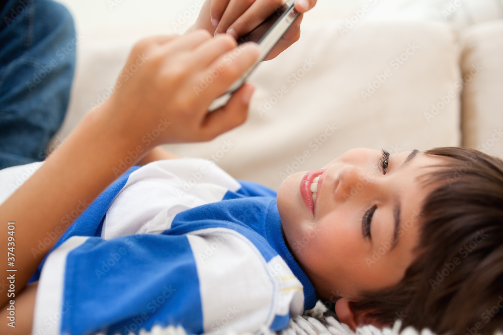 Boy lying on the carpet playing with his cellphone Boy lying on the carpet playing with his cellphone