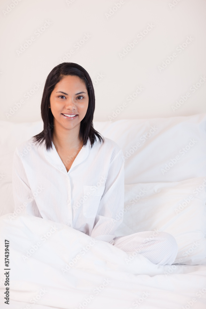 Smiling woman in pajamas sitting on the bed Smiling woman in pajamas sitting on the bed
