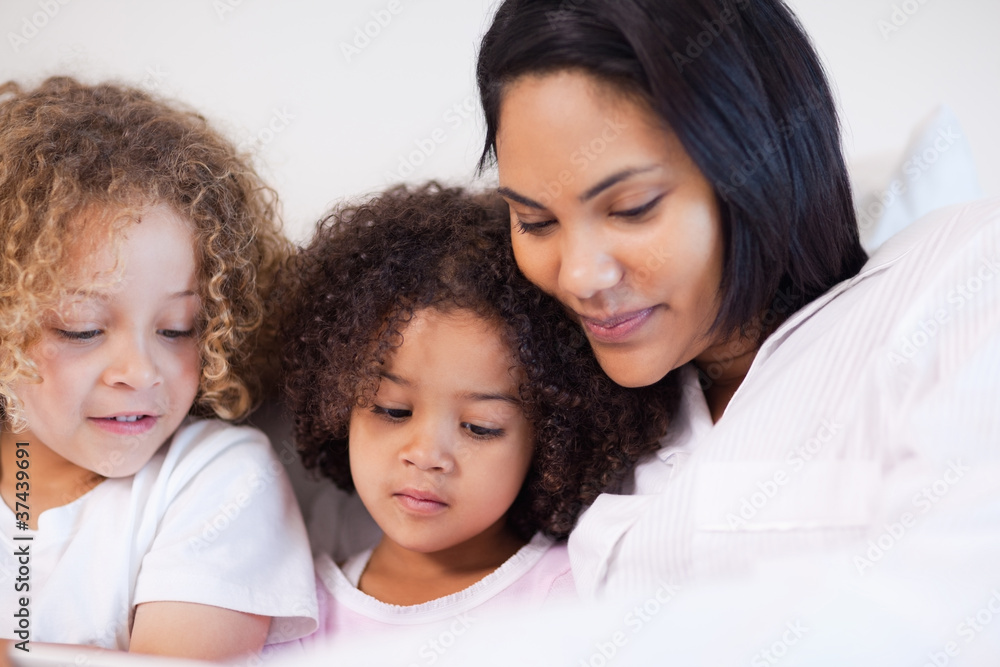 Woman sitting on the bed with her daughters Woman sitting on the bed with her daughters
