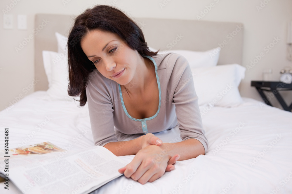 Woman laying on the bed reading a magazine Woman laying on the bed reading a magazine