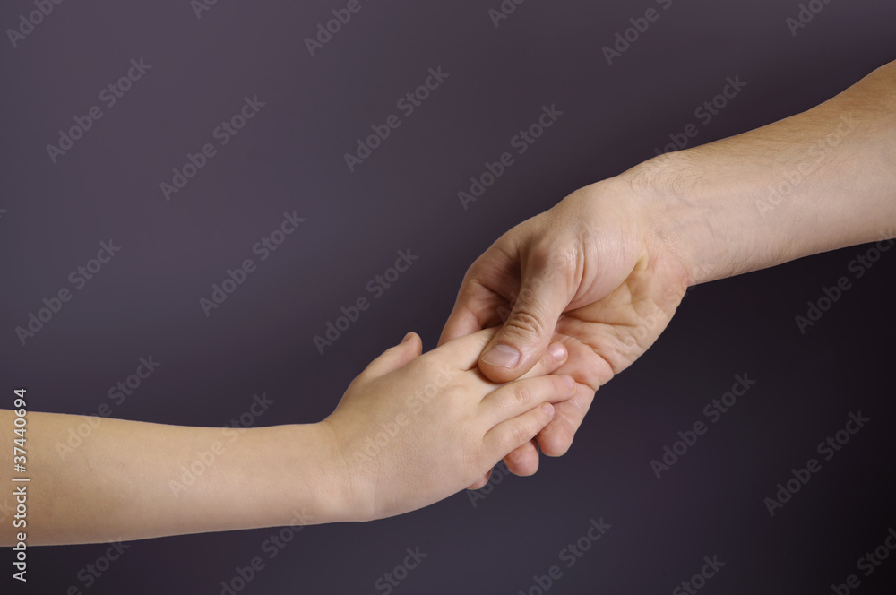 Father and child hands in the dark background