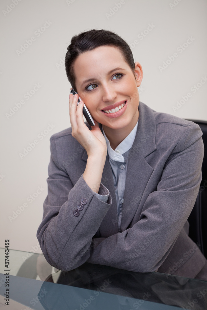 Businesswoman on the cellphone behind her desk Businesswoman on the cellphone behind her desk