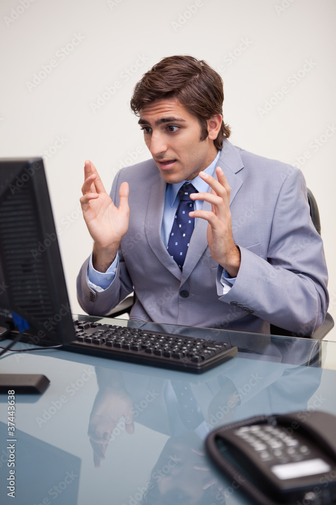 Businessman getting surprised by his computer Businessman getting surprised by his computer