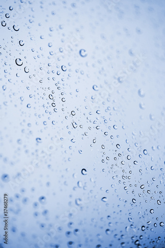 Beautiful abstraction with water drops over blue glass backgroun