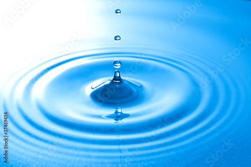 Transparent drop of water, falls downwards.