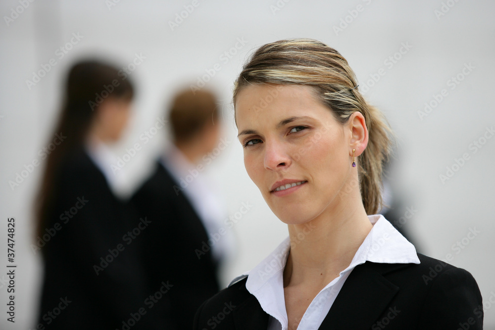 Blond woman stood with colleagues in background Blond woman stood with colleagues in background