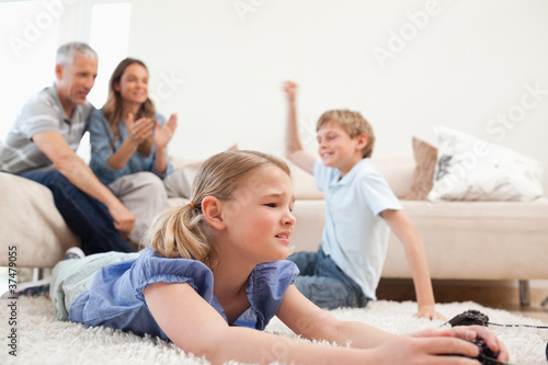Cute children playing video games with their parents on the back