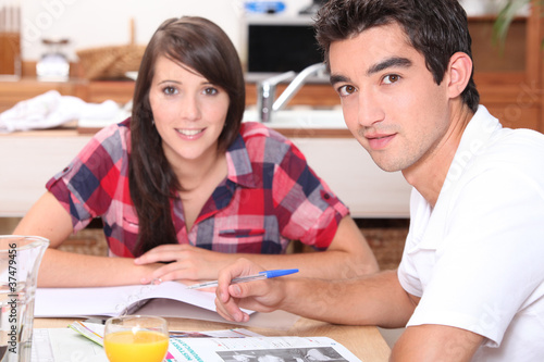 Young couple doing coursework at the kitchen table