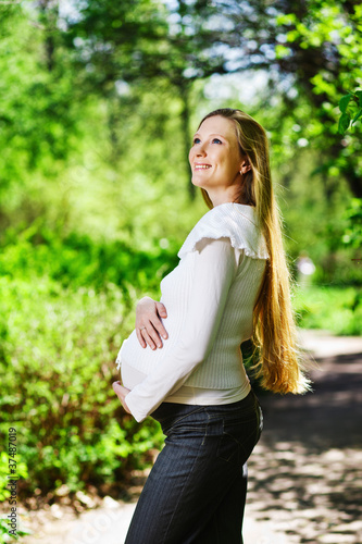Beautiful pregnant woman relaxing in the park