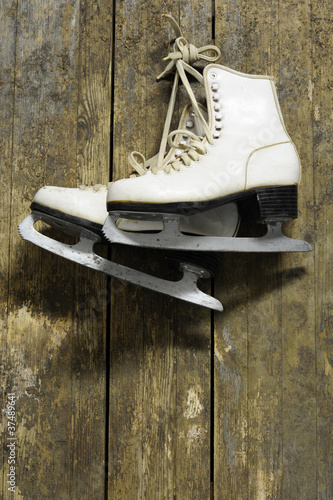 ice skates hanging on an old weathered wooden wall