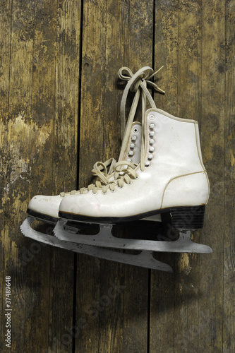 ice skates hanging on an old weathered wooden wall