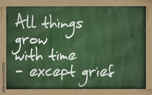 " All things grow with time - except grief " written on a blackb