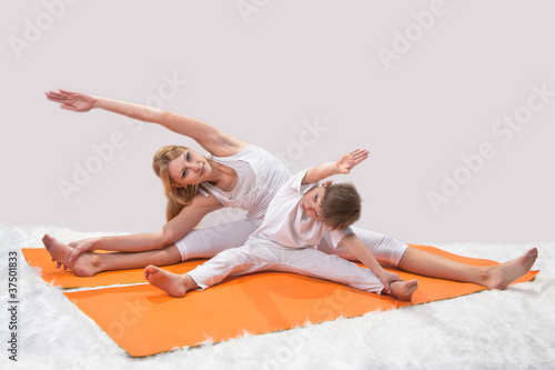 A beautiful young mother practices yoga with her son