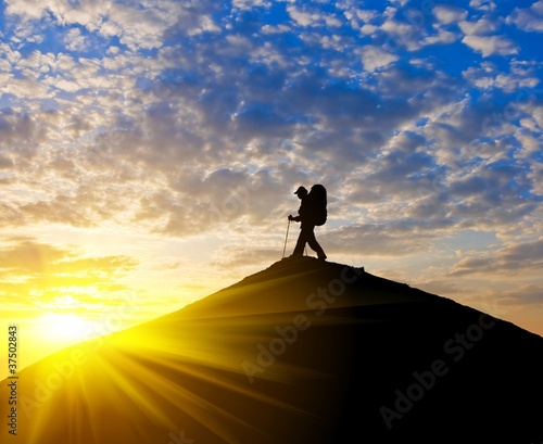 traveler silhouette on a mountain top at the sunset