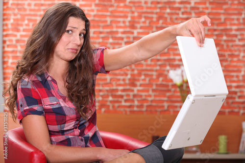 Woman holding her laptop disdainfully photo