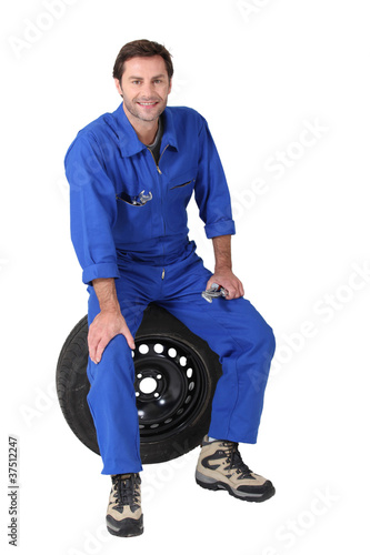 mechanic sitting on a tyre photo