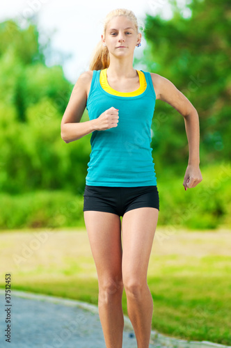 Young woman running in green park
