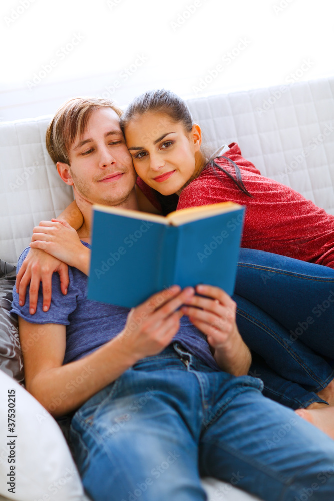 Romantic couple sitting on sofa and reading book