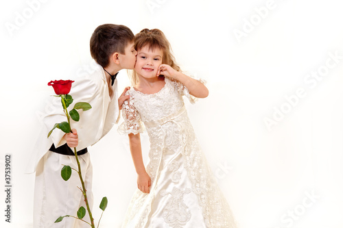 Little groom giving a kiss to a cute little bride