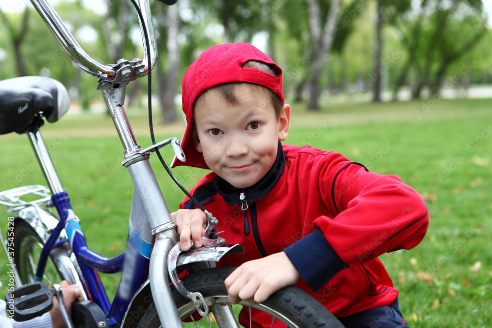 Naklejka premium Boy on a bicycle in the green park