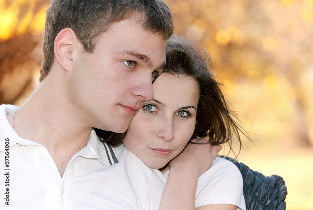 Naklejka premium Closeup portrait of a cute young couple together with arms aroun