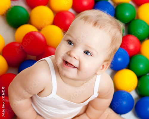Portrait of a smiling infant sitting among colorful balls