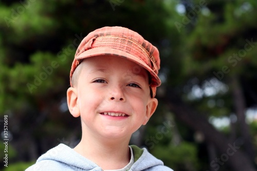 Small child in a cap looking straight and smiling